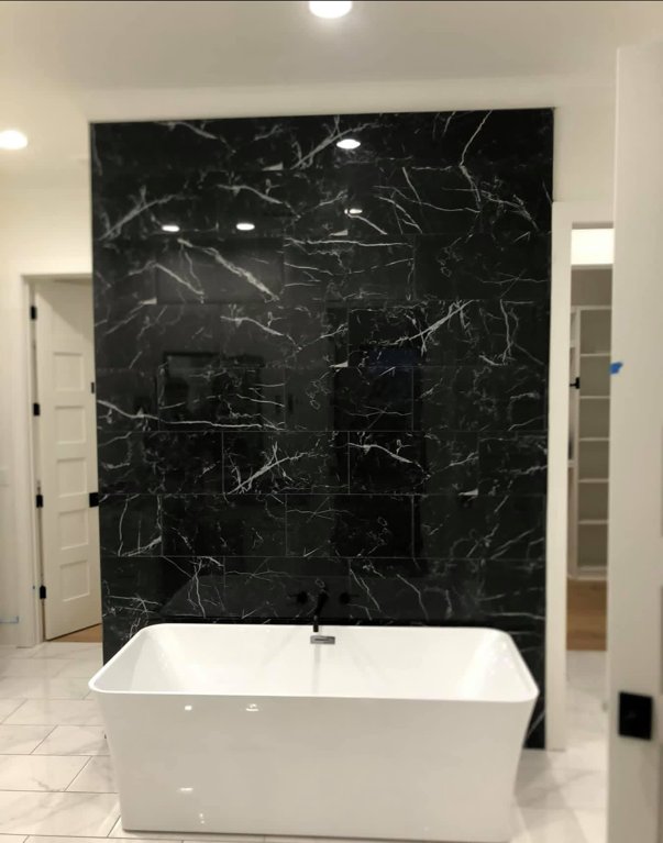 Custom master bath with marble accent wall and freestanding tub